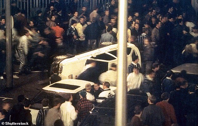 Football hooliganism continued into the 1990s. Pictured is the scene after a fight following the match between Millwall and Derby in 1994, which saw hooligans turning over a car