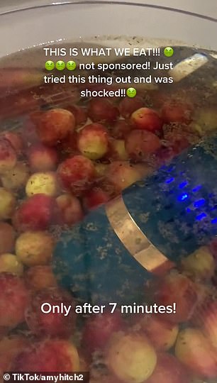 Es zeigt, wie sie das Reinigungsgerät in eine Schüssel mit Leitungswasser mit Weintrauben legt
