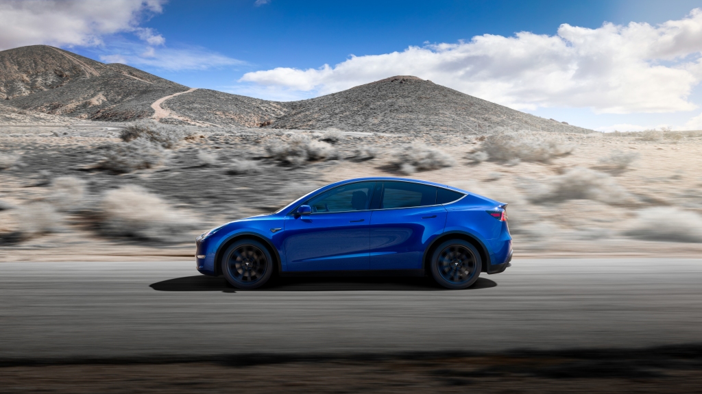 Blaue Tesla Model Y-Seitenansicht auf einsamer Autobahn