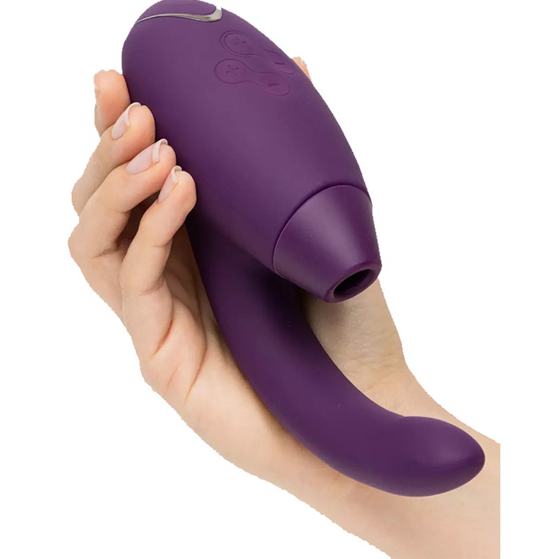 Eine Hand, die das violette Sexspielzeug Womanizer X Lovehoney InsideOut Stimulator auf einem weißen Hintergrund hält