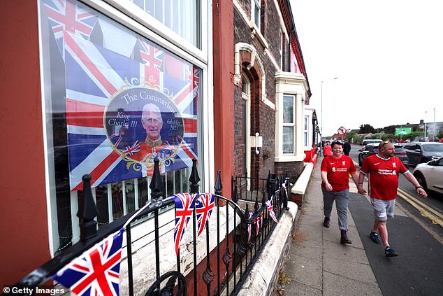 Ein Banner in einem Fenster feiert die Krönung von Charles III und Camilla, während Liverpool-Fans zum Aufeinandertreffen ihrer Mannschaft gegen Brentford in Anfield aufbrechen
