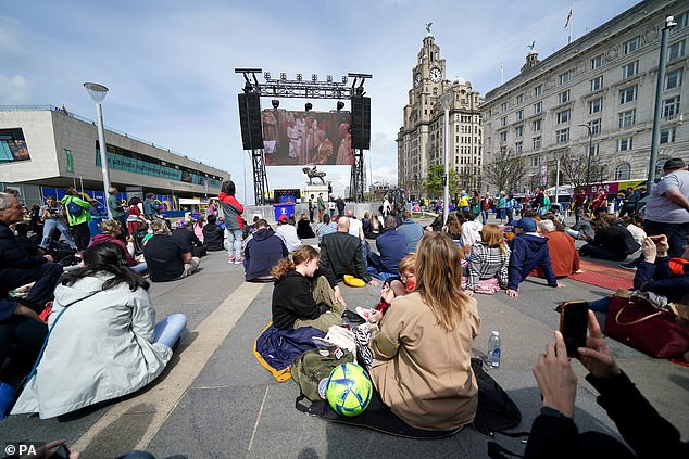 Mitglieder der Öffentlichkeit verfolgen die Krönung von König Karl III. und Königin Camilla auf einer großen Leinwand im Eurovision Village, Liverpool