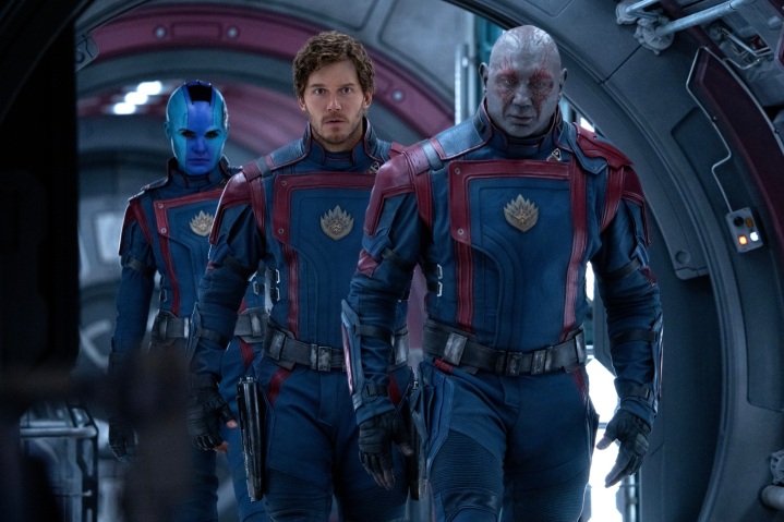 „Guardians of the Galaxy Vol.  3' Nebula (Karen Gillan), Star-Lord (Chris Pratt) und Drax (Dave Bautista) tragen schwarze und rote Uniformen und gehen einen Schiffskorridor aus Metall entlang.