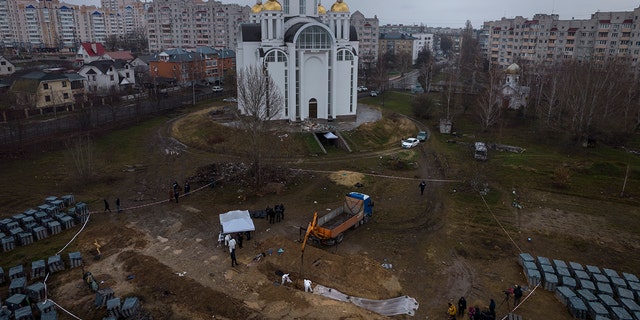 Friedhofsarbeiter arbeiten an einem Massengrab in Bucha am Stadtrand von Kiew, Ukraine, um Zivilisten zu identifizieren, die während des Krieges gegen Russland getötet wurden, Sonntag, 10. April 2022.