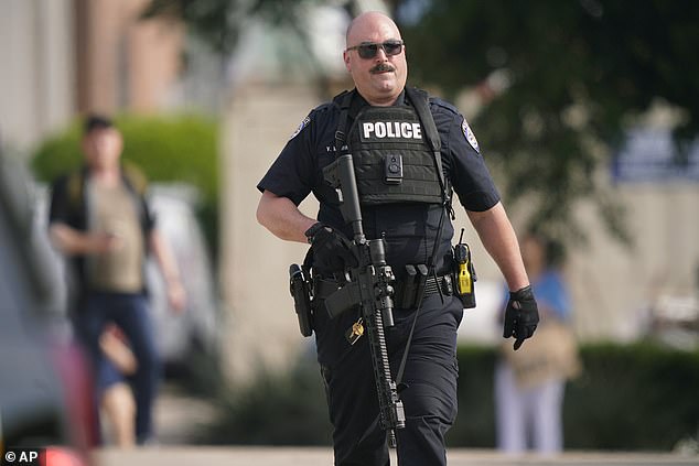Ein Polizeibeamter trägt ein Gewehr, während Menschen aus dem Einkaufszentrum evakuiert werden