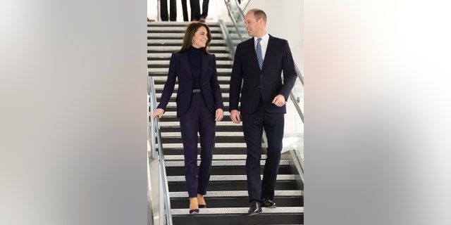 Prinz William und Kate Middleton in passenden schwarzen Outfits gehen eine Treppe hinunter