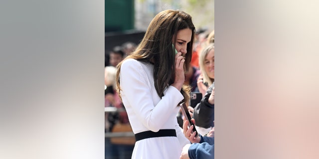 Kate Middleton in einem schwarz-weißen Kleid telefoniert mit einem Handy