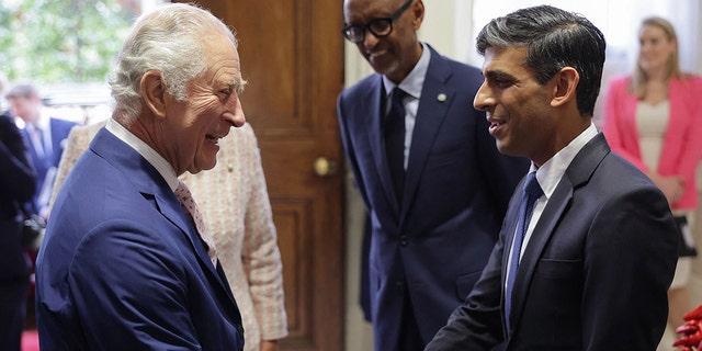 König Charles in einem blauen Anzug wird vom britischen Premierminister begrüßt