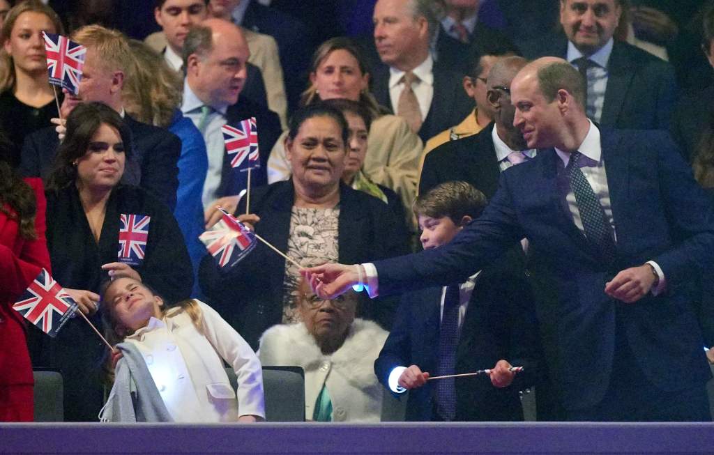 Prinzessin Charlotte von Wales (L) reagiert, beobachtet von ihrem Bruder, dem britischen Prinzen George von Wales (C), während ihr Vater, der britische Prinz William, Prinz von Wales (R), während des Krönungskonzerts auf Schloss Windsor in Windsor mit einer Unionsflagge spielt. westlich von London am 7. Mai 2023.