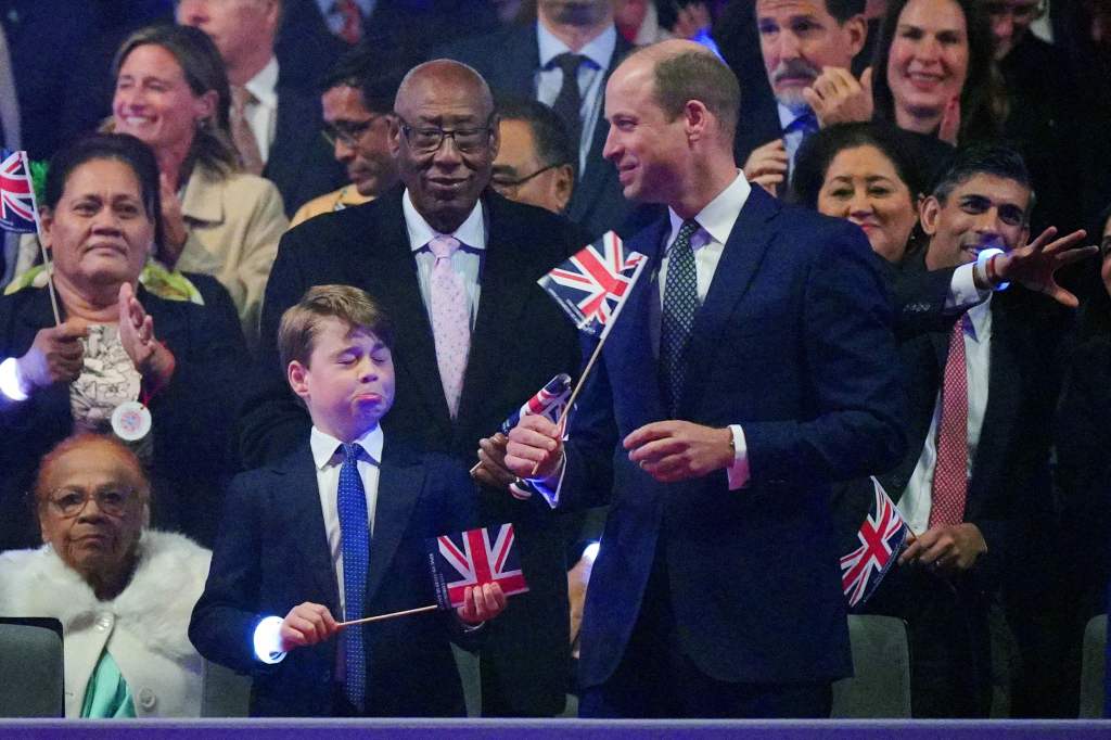 Der britische Prinz George von Wales (L) reagiert, als sein Vater, der britische Prinz William, Prince of Wales (R), während des Krönungskonzerts auf Schloss Windsor in Windsor, westlich von London, am 7. Mai 2023 mit einer Flagge der Union spielt. - Zum ersten Mal Auf der Ostterrasse von Schloss Windsor findet jedes Mal ein spektakuläres Live-Konzert statt, das auch in über 100 Ländern auf der ganzen Welt zu sehen sein wird. 