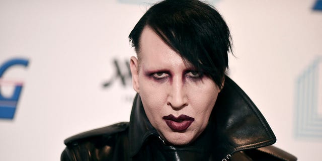 Marilyn Manson läuft mit schwarzer Lederjacke und Lippenstift über den roten Teppich
