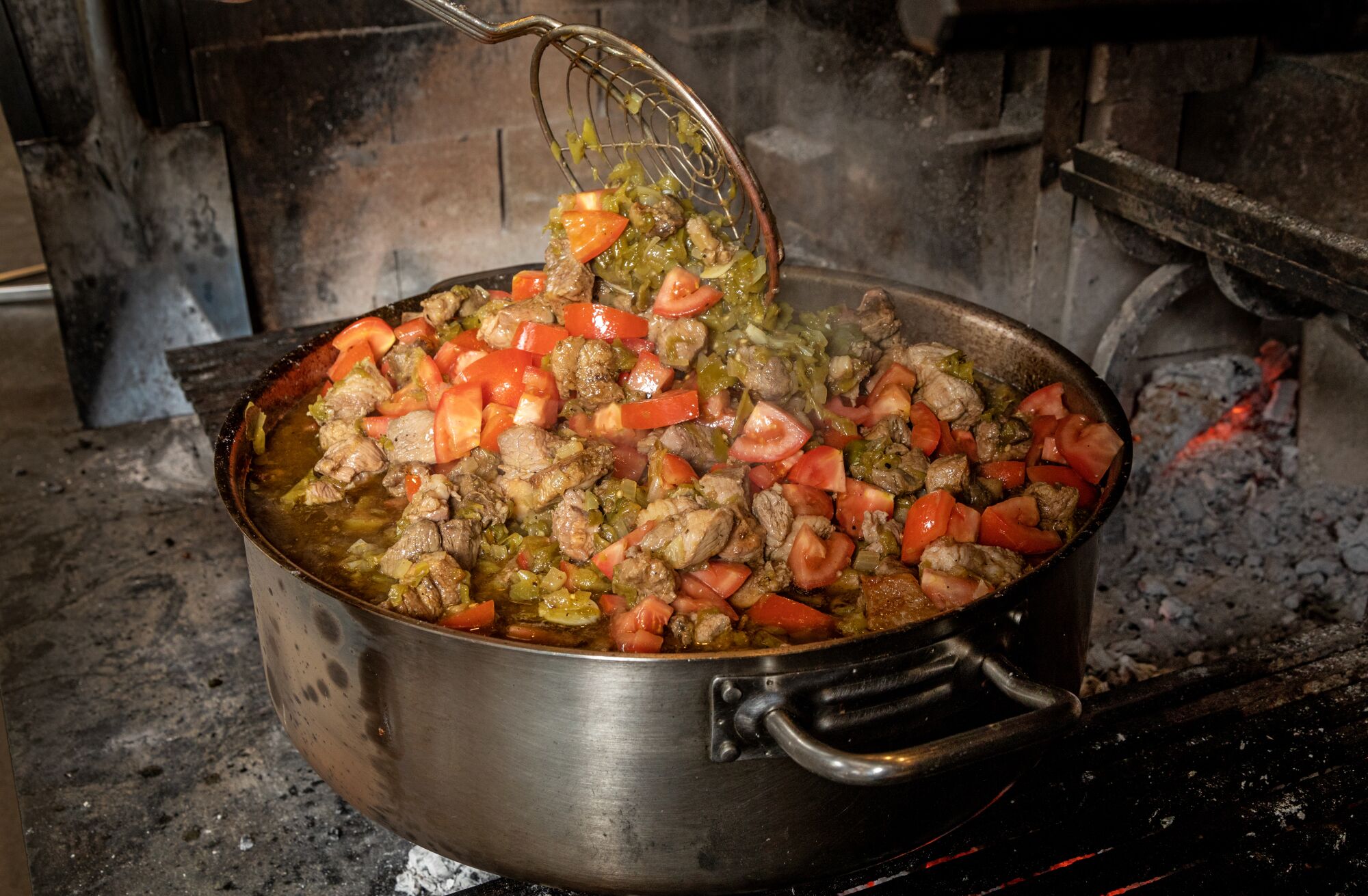 Bei Dunsmoor in Los Angeles ein großer Topf oder Eintopf gefüllt mit Schweinefleischstücken, Chilis und Tomaten.