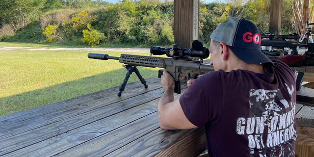 Ein Mann, der Merchandise-Artikel von Gun Owners of America trägt, schießt mit einem Gewehr