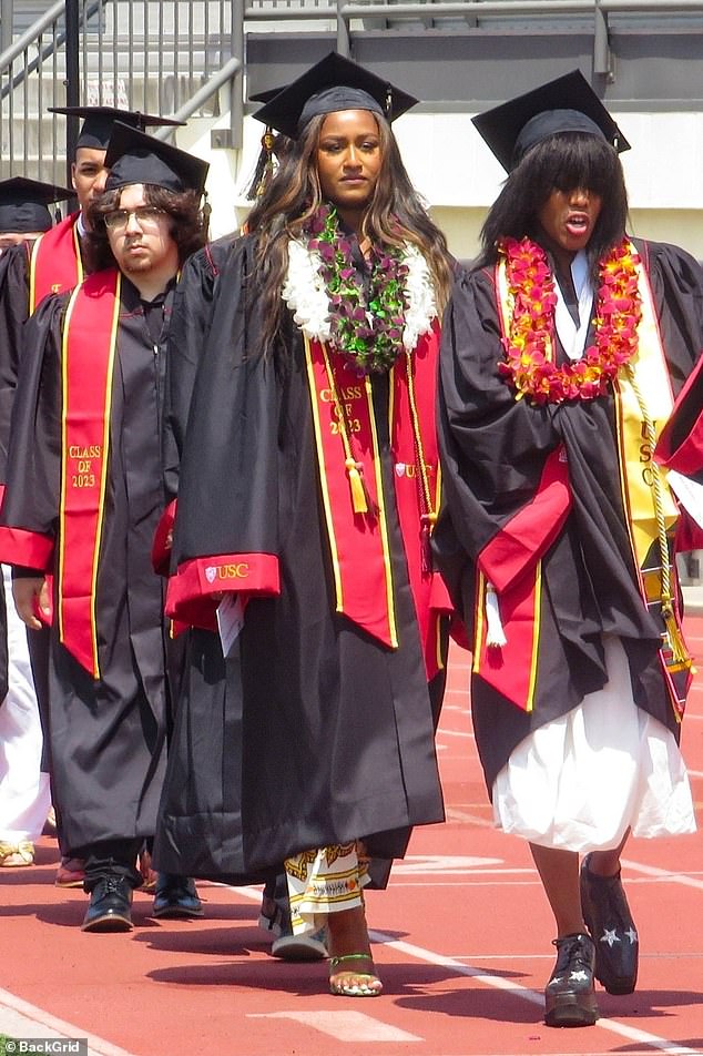 Sasha trug wie die anderen Absolventen eine schwarze Mütze und ein Kleid mit USC-Wappen und Kardinalspaspeln, die sie über einem gemusterten cremefarbenen Maxikleid trug