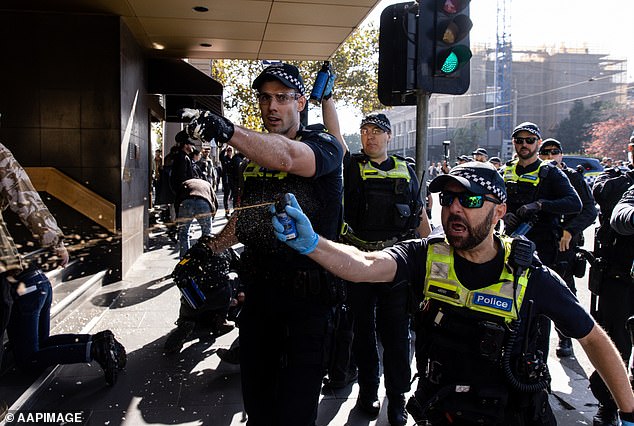 Auf Fotos ist zu sehen, wie Polizisten scheinbar Flüssigkeit auf Menschenmengen sprühen, um sie aufzulösen