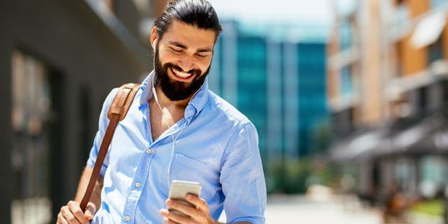 Lächelnder Mann im blauen Hemd mit Smartphone