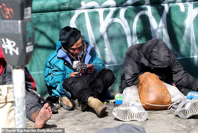 Menschen rauchen offen Drogen auf dem Bürgersteig des Tenderloin-Viertels von San Francisco, wo die Zahl der Todesfälle durch Überdosierung in den letzten Monaten sprunghaft angestiegen ist