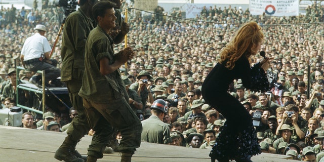 Truppen tanzen auf der Bühne mit Ann-Margret, die in Schlaghosen singt