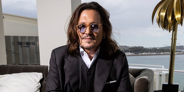 Johnny Depp trägt einen schwarzen Anzug mit Hemd und Brille 