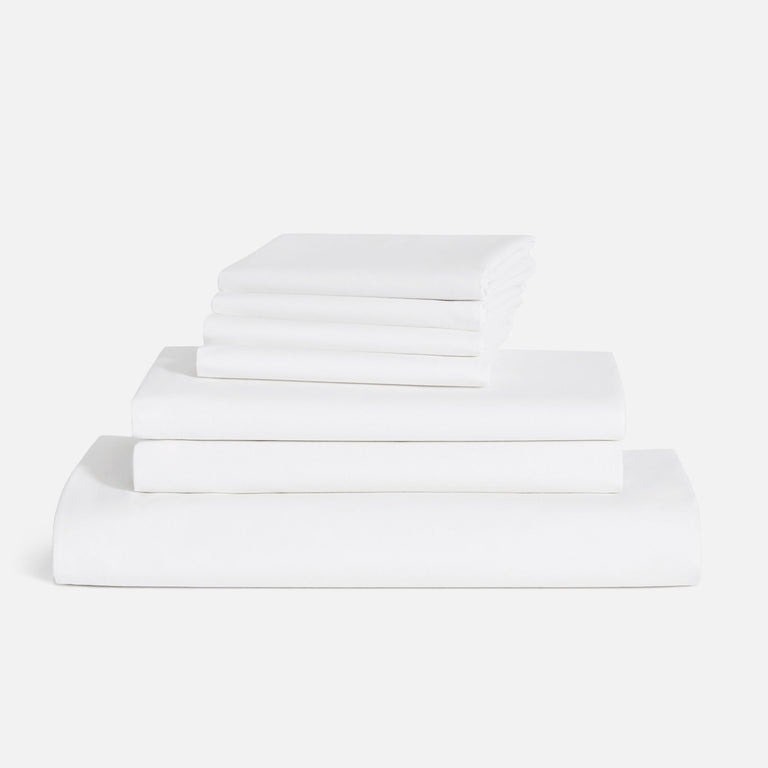 Brooklinen Luxe Sateen Bettwäsche Hardcore Bundle Stapel gefalteter weißer Laken auf weißem Hintergrund