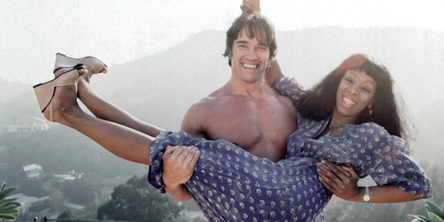 Arnold Schwarzenegger hält Donna Summer hoch