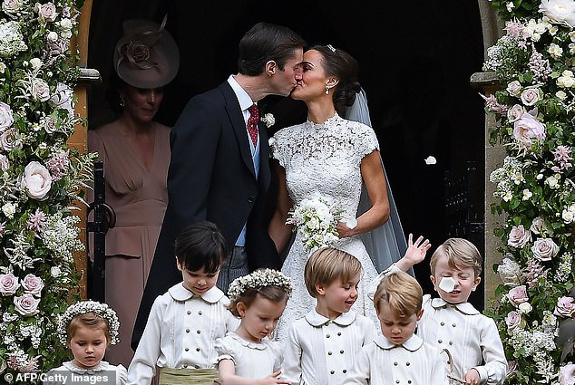Pippa and James kiss as their bridesmaids and page boys throw flower petals