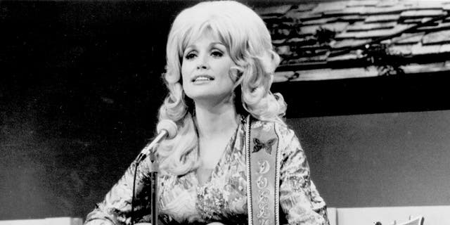 Ein Foto von Dolly Parton, die 1974 Gitarre spielt.