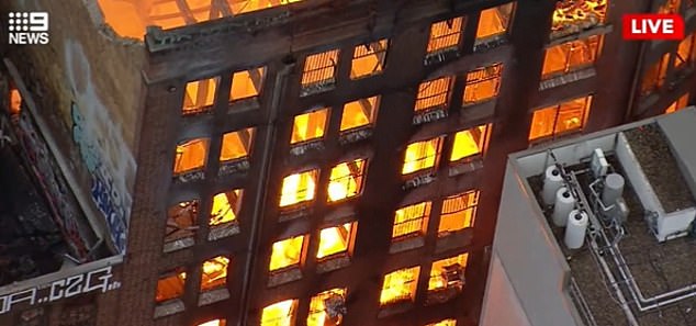 Fast jeder Raum des Gebäudes brennt, während Wände und Dach auf die Straße darunter einstürzen