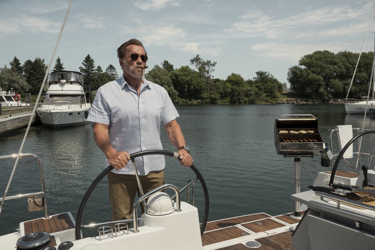 Arnold Schwarzenegger mit Sonnenbrille steuert ein Boot