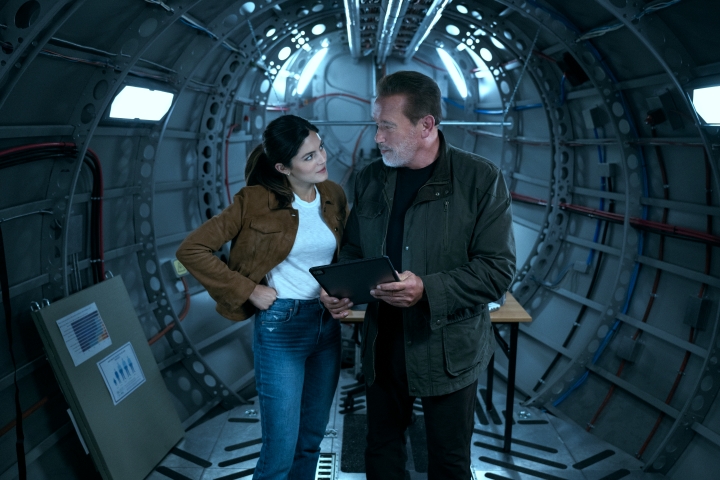Monica Barbaro und Arnold Schwarzenegger stehen in FUBAR gemeinsam in einem Frachtflugzeug.