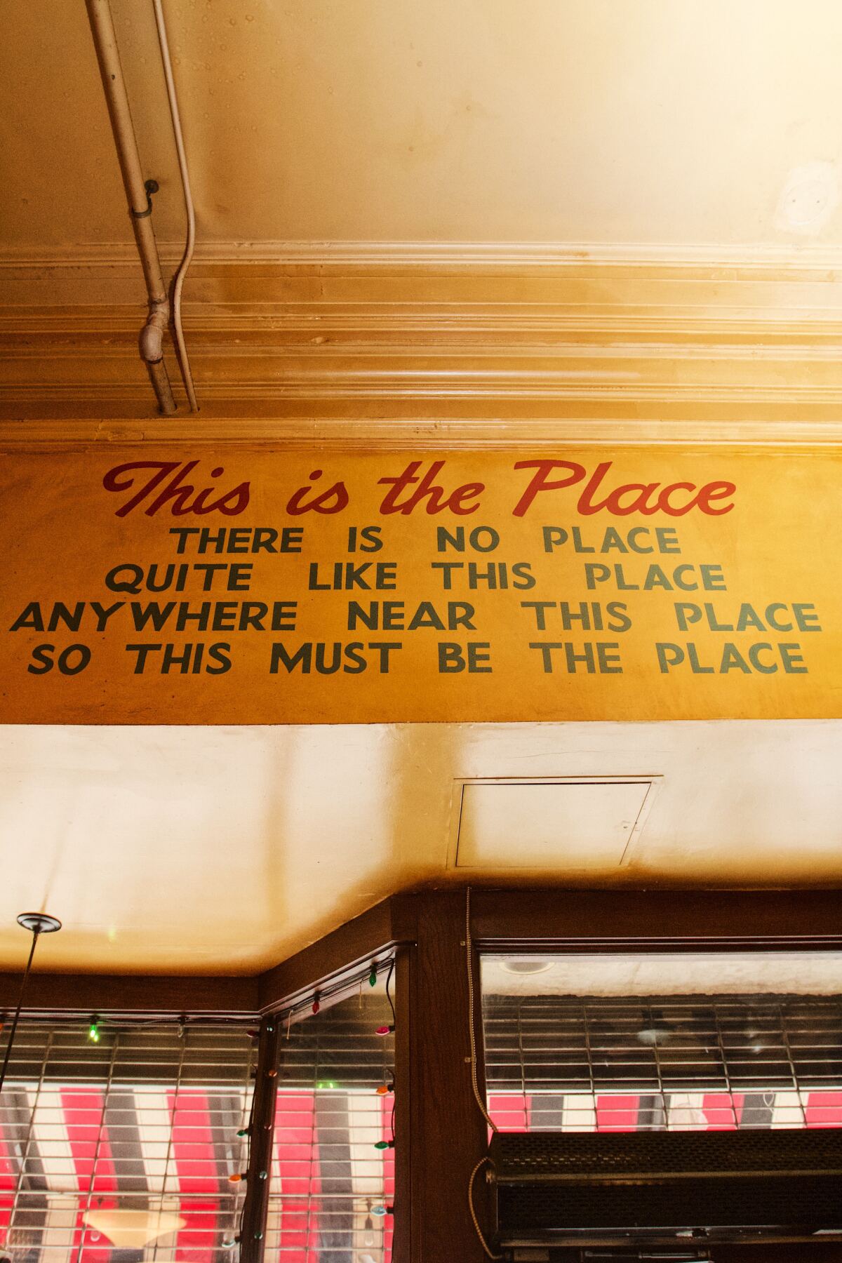 Ein Schild mit der Aufschrift „Dies ist der Ort, es gibt keinen Ort / so etwas wie diesen Ort irgendwo in der Nähe dieses Ortes.“" über der Haustür
