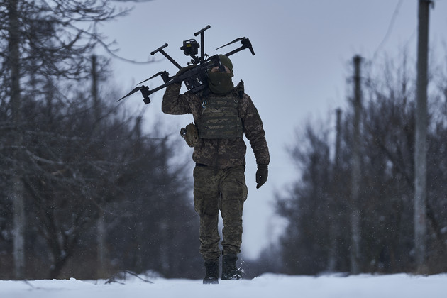 Ein ukrainischer Soldat trägt eine Drohne nahe der Frontlinie.