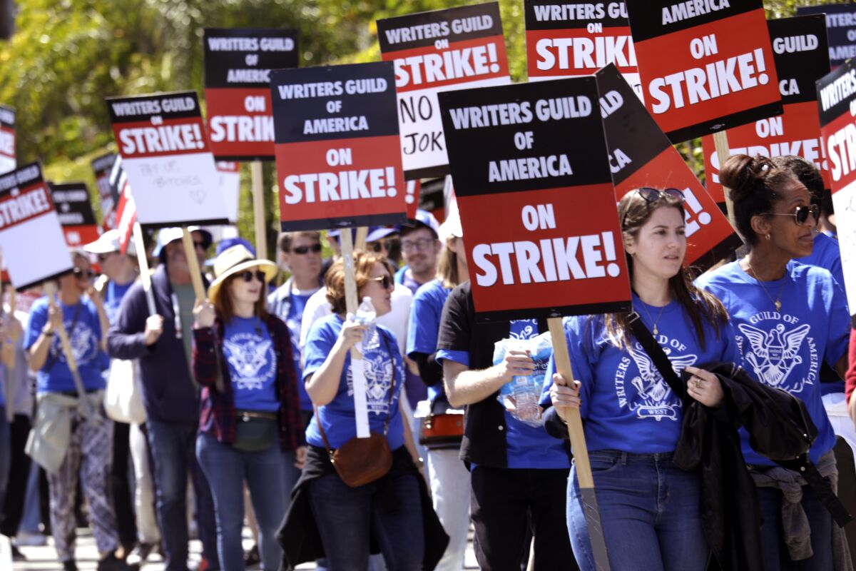 eine Menschenmenge in einer Streikpostenlinie mit schwarzen und roten Schildern "Writers Guild of America im Streik!"