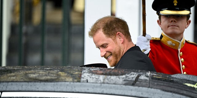 Ein lächelnder Prinz Harry, der in ein schwarzes Auto einsteigt