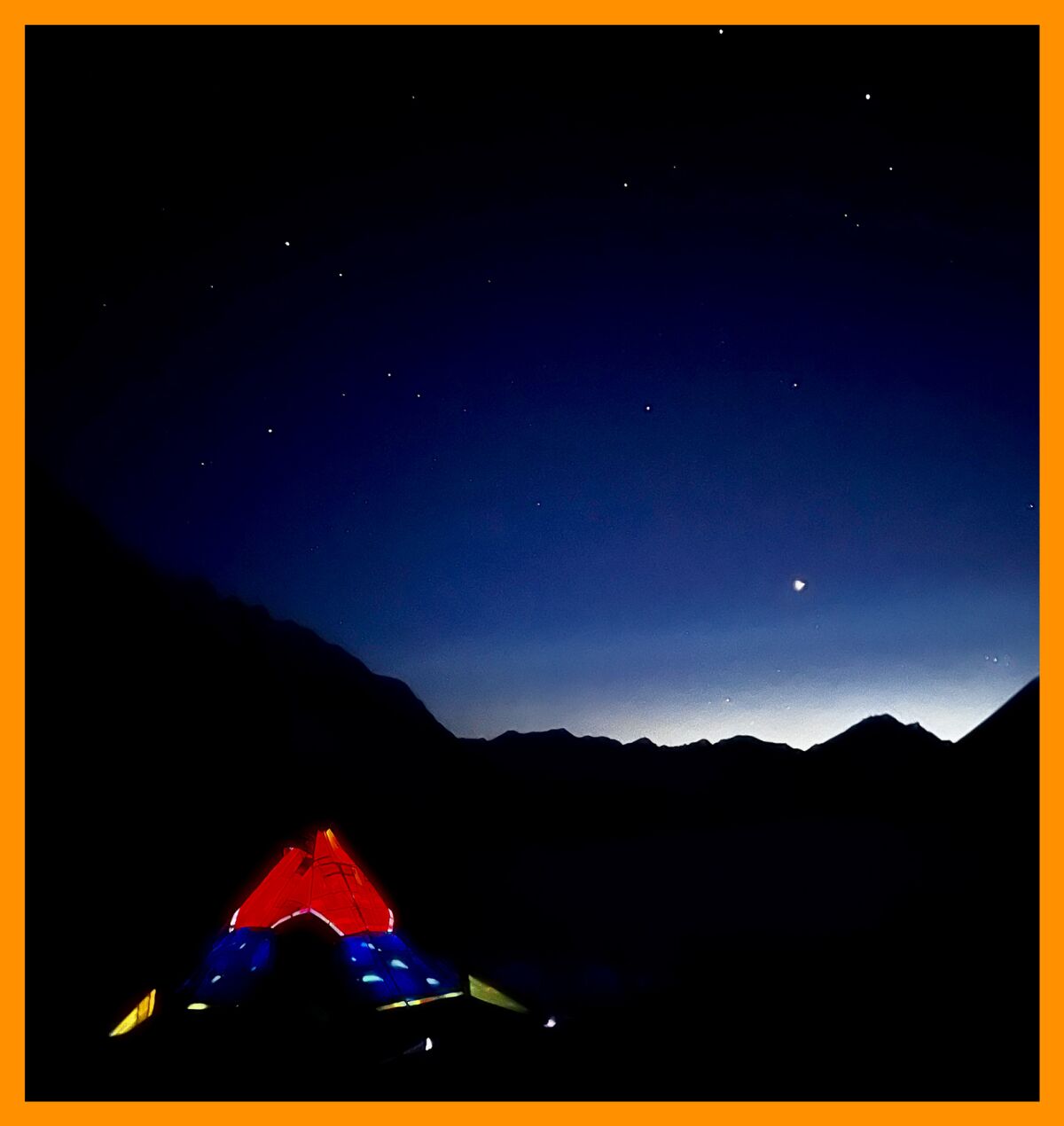 Das Zelt wird von innen vor dem sternenklaren Nachthimmel beleuchtet.