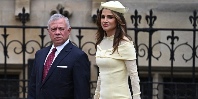 Jordans King Abdullah II Ibn Al Hussein in a suit next to queen rania in a yellow dress