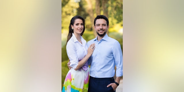 Princess Rajwa in a white blouse and colorful skirt next to Crown Prince Hussein in a light blue shirt