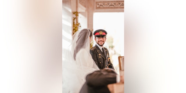 The royal bride and groom of Jordan looking at each other in a bridal gown and military suit