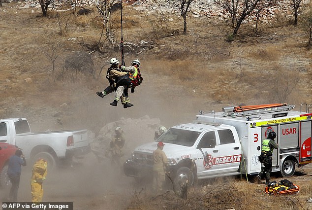 Zwei Rettungskräfte klammern sich fest, während sie aus der Luft geborgen werden, während die Behörden am Dienstag in Jalisco, Mexiko, mit mehreren Säcken voller menschlicher Überreste arbeiten