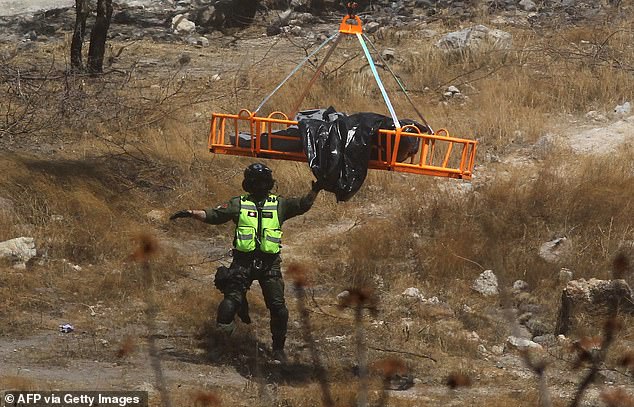 Ein Rettungsdienstmitarbeiter führt einen Beutel voller menschlicher Überreste, der am Dienstag von einem Hubschrauber in Jalisco, Mexiko, geflogen wird