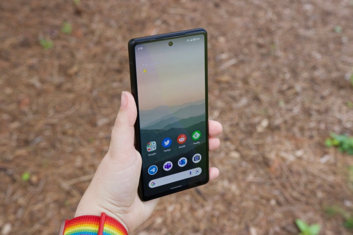 Someone holding the Google Pixel 6a. The display is on and showing the phone's home screen.