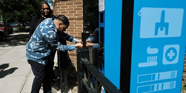 Ein Mitarbeiter des Dienstes für unterversorgte Menschen eröffnet einen neuen Verkaufsautomaten für das öffentliche Gesundheitswesen