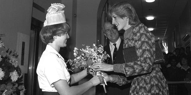 Ein Schwarz-Weiß-Foto von Prinzessin Diana, die von einer Krankenschwester einen Blumenstrauß erhält