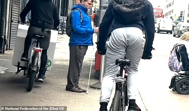 Ein Lastenfahrradfahrer und ein weiterer Radfahrer umgehen einen blinden Mann, der an der Bushaltestelle wartet, und eine Frau im Rollstuhl (rechts), die versucht, an einer „schwimmenden“ Bushaltestelle an der Lea Bridge Road im Waltham Forest im Norden in den Bus einzusteigen. Ost-London am 29. März