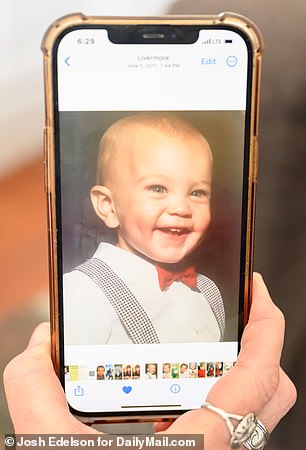 Jacqui holds up a picture of her son Corey as a toddler. On the day she speaks to DailyMail.com, it is his 32nd birthday