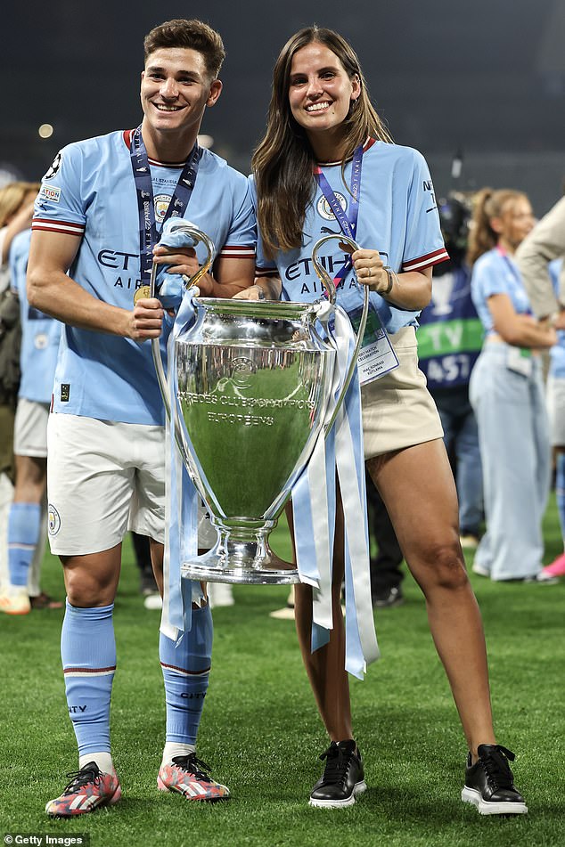 Julian Alvarez of Manchester City and girlfriend Maria Emilia Ferrero pose with the UEFA Champions League trophy