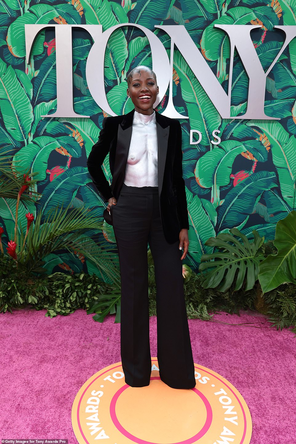 Gorgeous: Lupita paired the eye-catching piece with black trousers and a matching blazer, slung over one shoulder after taking it off on the red carpet