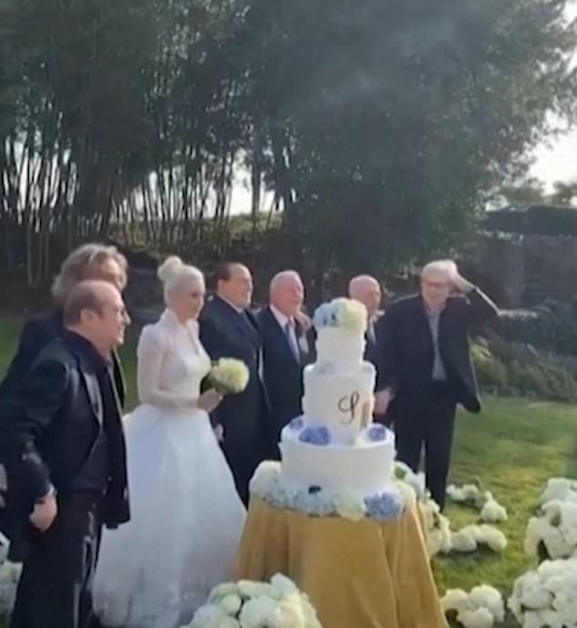 Berlusconi can be seen on the left of the picture, stood alongside Ms Fascina who is wearing a white wedding dress and holding a bouquet of flowers