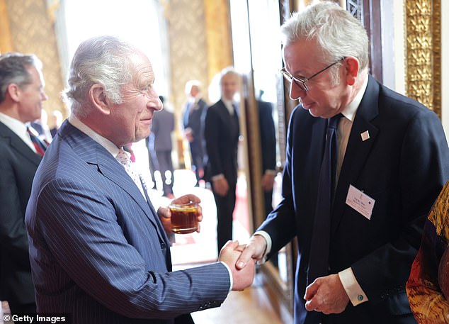 König Charles schüttelt Michael Gove während eines Empfangs anlässlich des 75. Jahrestages der Ankunft von HMT Empire Windrush die Hand