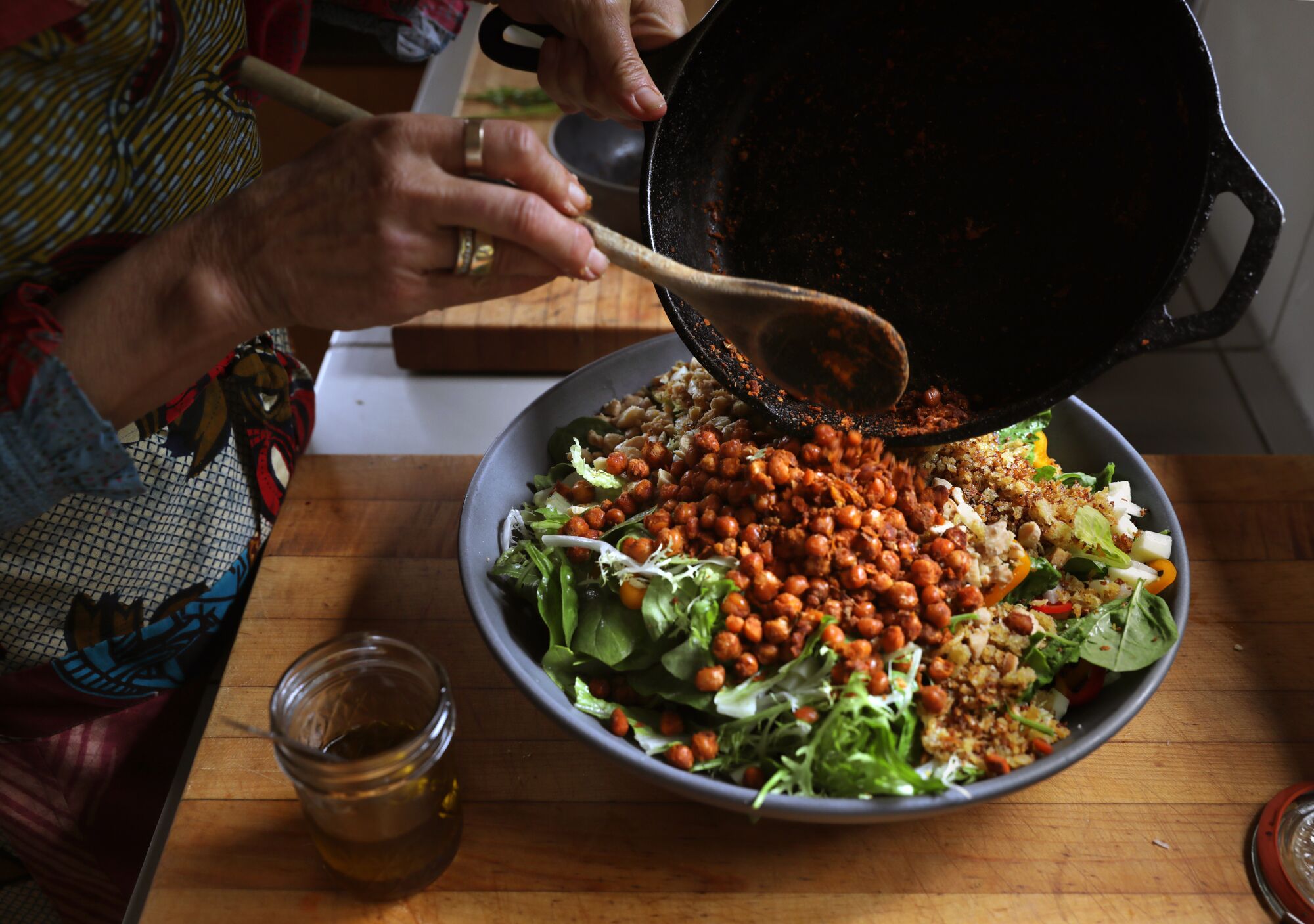 Hände bereiten eine große Schüssel mit gehacktem Salat zu.